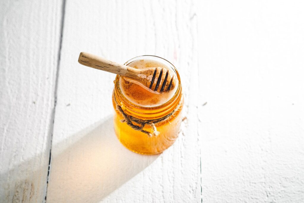 Miel s'écoulant d'une cuillère à miel dans un bol en verre
