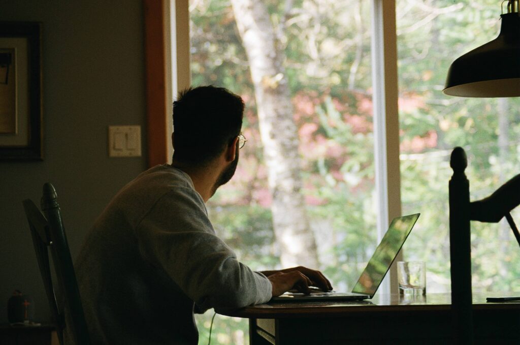 stress au travail, homme regardant par la fenêtre face à son PC portable