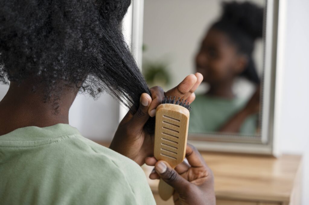 femme d'origine africaine qui se brosse les cheveux face au miroir