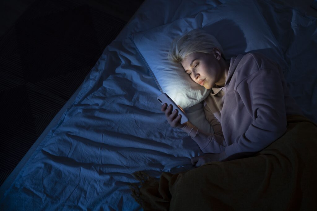 femme avec le téléphone à côté dans son lit