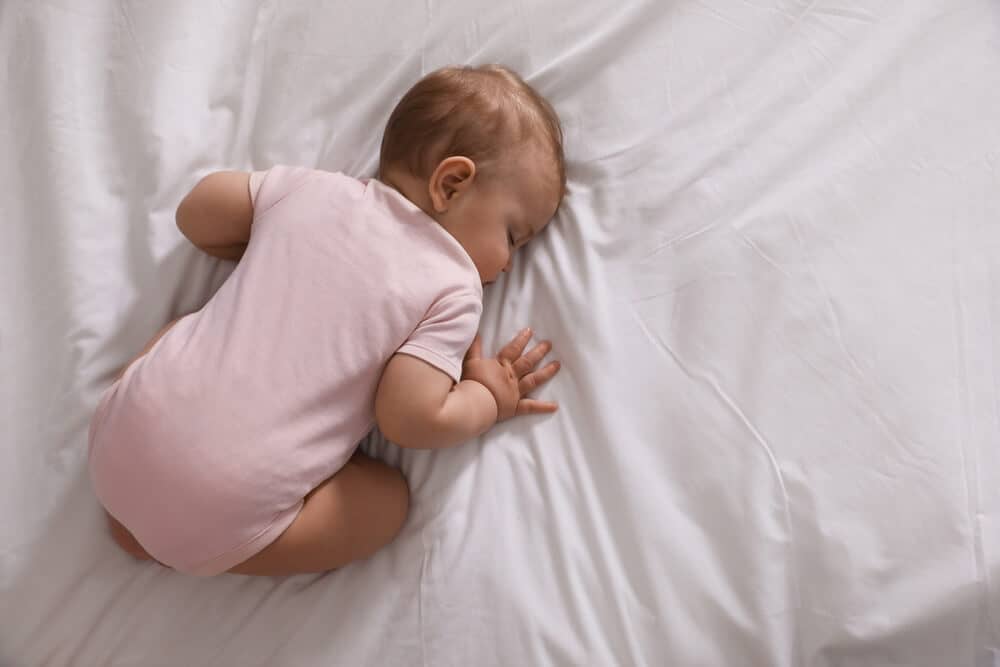 bebe fille qui dort sur le ventre