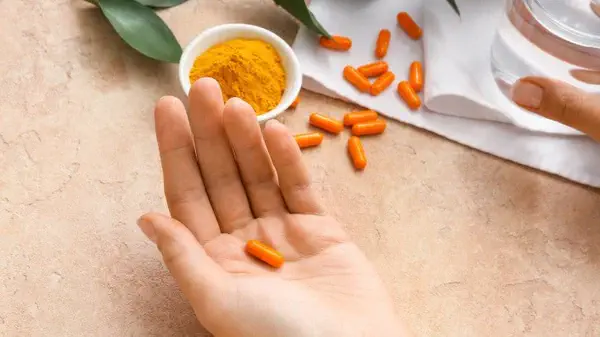 quel est le meilleur curcuma pour la santé main qui tient une gélule de curcuma comprimés à prendre pour ses bienfaits santé peau digestion