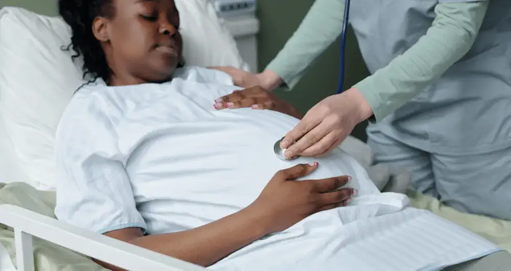 femme enceinte de couleur noire tenant son ventre avec medecin hopital accouchement
