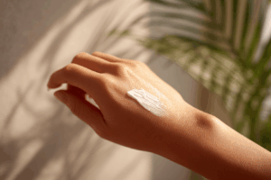 Personne appliquant doucement une crème naturelle ou un baume sur le bras pour apaiser une peau sèche et irritée, ambiance calme et rassurante, lumière naturelle douce, esthétique bien-être et soins de la peau, photographie réaliste.