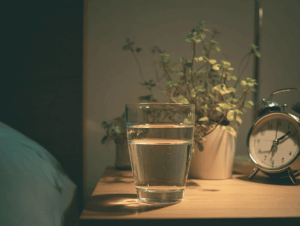 verre d'eau transparent posé sur une table de nuit
