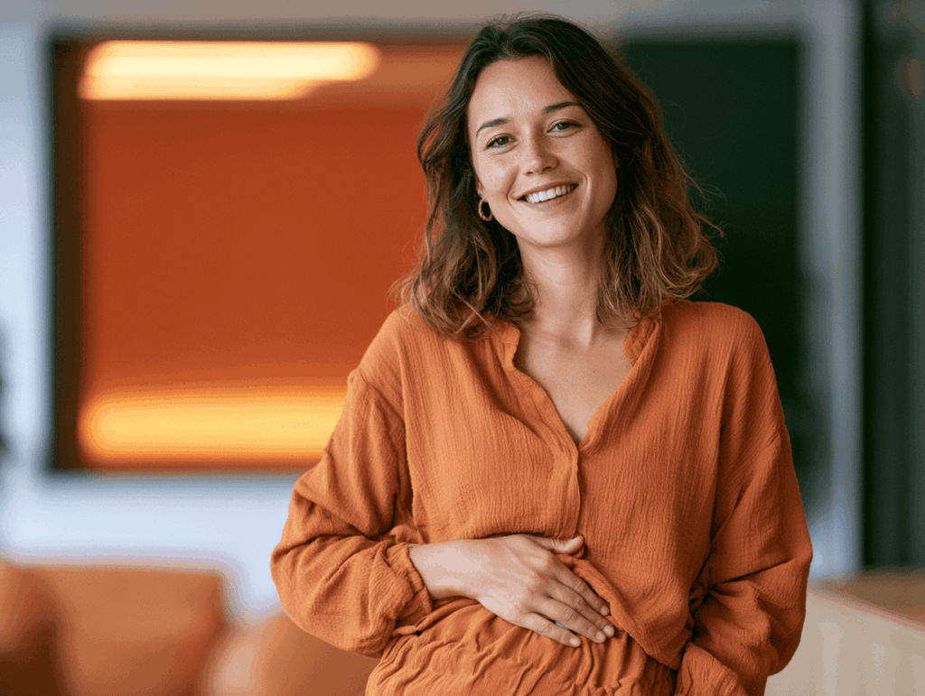 Photo d'une personne souriante se tenant le ventre légèrement, ambiance bien-être et confort digestif, lumière douce.