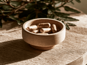 Photo de gélules de berbérine dans un petit bol en céramique posé sur une table en bois clair, lumière naturelle.