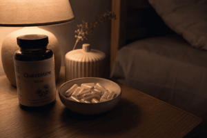 Photo de gélules de quercétine dans un petit bol posé sur une table de chevet, ambiance nocturne douce et tamisée.