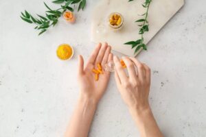 meilleur curcuma effet secondaire anticoagulant santé main qui tient une gélule de curcuma comprimés à prendre pour ses bienfaits santé peau digestion